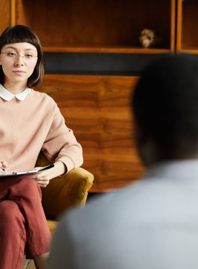 Young woman sitting on armchair during her psychology therapy and talking to psychologist